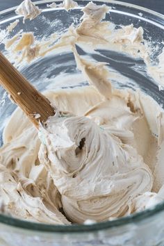 a wooden spoon mixing cream in a glass bowl