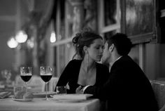 a man and woman sitting at a table with glasses of wine in front of them