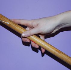 a woman's hand holding onto a wooden stick