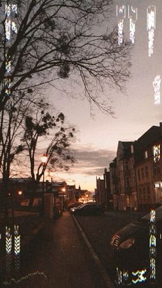 a street with cars parked on the side of it at night and trees in the background