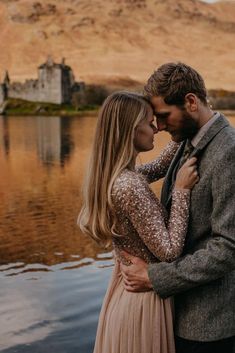 a man and woman standing next to each other in front of a body of water