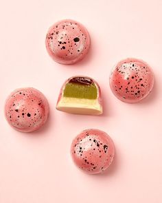 some pink and black speckled candy on a pink surface with three pieces of cake