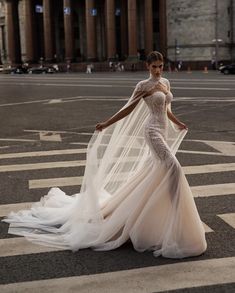 a woman is standing in the middle of an empty street wearing a wedding dress and veil