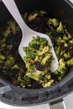 broccoli is being cooked in an air fryer with a spatula inside