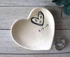 a heart shaped dish with two wedding rings next to it