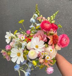 a person holding a bouquet of flowers in their hand on the street with no one around