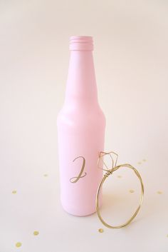 a pink bottle with a gold ring next to it