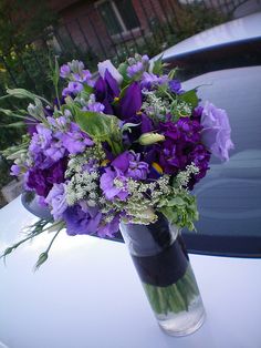 a vase filled with purple flowers sitting on top of a white car