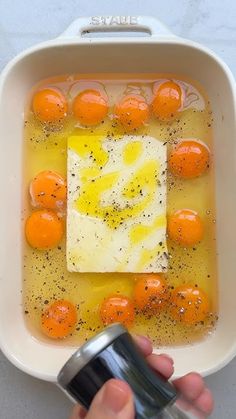 a person is holding a can in a bowl filled with oranges