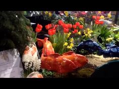 there are many colorful flowers and plants in this garden shop window display, including red tulips with yellow daffodils