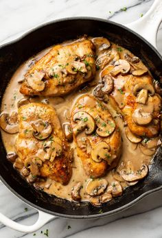 chicken with mushrooms and gravy in a cast iron skillet on a marble countertop