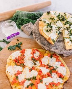 two small pizzas on wooden boards with cheese and vegetables next to them, along with other ingredients