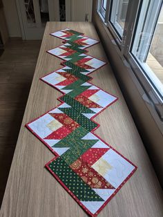 three rows of quilted table runneres on a long counter in front of a window