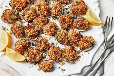 a white plate topped with cooked oysters and lemon wedges