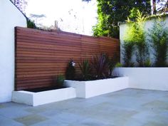 an outdoor area with white walls and wooden slatted fence, planters on either side