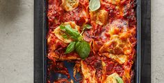 a pan filled with lasagna shells covered in sauce and fresh basil garnish