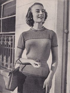 an old black and white photo of a woman holding a purse in front of a building