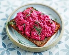 a plate topped with bread covered in pink spread and sprigs on top of it