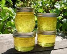 three jars filled with yellow liquid sitting on top of a wooden table