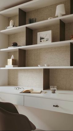 a white desk topped with lots of shelves filled with books and glasses next to a chair