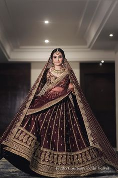 a woman in a maroon and gold bridal gown