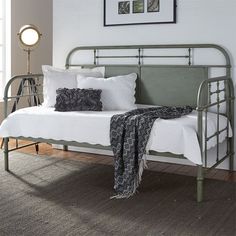 a metal day bed with white sheets and pillows