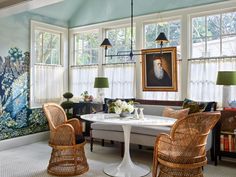 a living room with wicker chairs and paintings on the walls, two tables in front of them