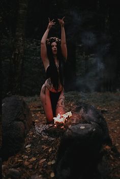 a woman sitting on top of a fire in the woods