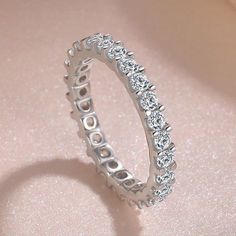 a white gold diamond ring on a pink background