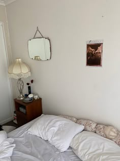 an unmade bed with white sheets and pillows in a bedroom next to a door