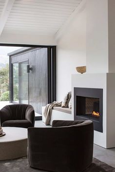 a living room with two chairs and a fire place in the middle of the room