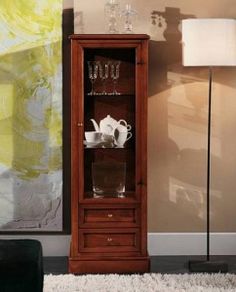 a tall wooden cabinet sitting next to a lamp on a rug in a living room