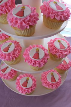 cupcakes with pink frosting on a three tiered cake stand