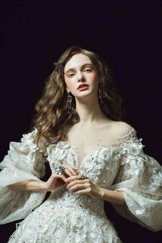 a woman in a white dress is posing for the camera with her hands on her hips