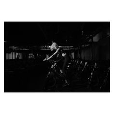 black and white photograph of a person riding a bike in a dark room with lots of chairs