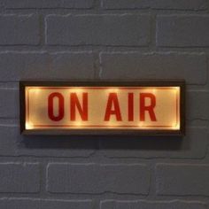 an on air sign is lit up against a brick wall with the word on it