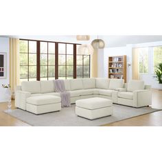 a living room with a large sectional couch and footstool in front of a window