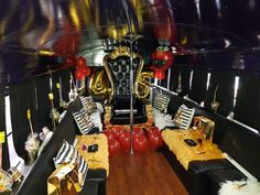 the inside of a party bus decorated with black and gold furniture, balloons, and decorations