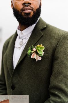 a man with a beard wearing a green suit and flower boutonniere on his lapel