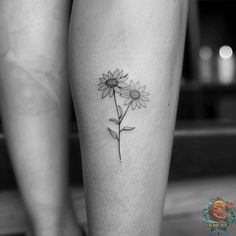 a black and white photo of a woman's leg with a flower tattoo on it