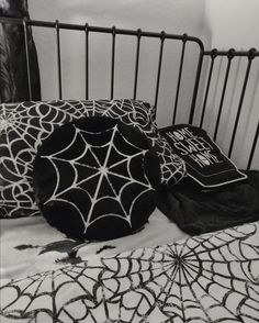 black and white photograph of spiderweave pillows on a crib with an iron headboard