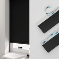 two black roller shades and one white roller shade with blue writing on them, both in the same window sill