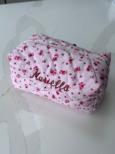 a pink flowered bag with the name margie on it sitting on a table