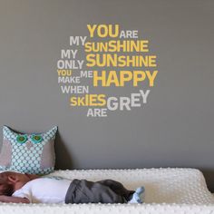 a baby sleeping on top of a bed next to a wall with words painted on it