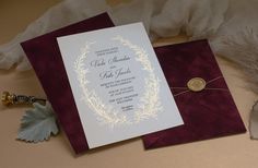 a wedding card with a wax stamp on it sitting next to a feather quill