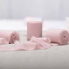 three rolls of pink toilet paper sitting on top of a white table cloth next to each other