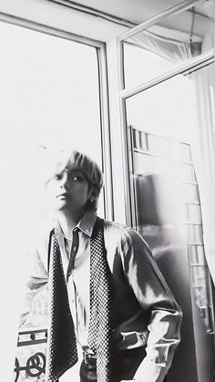 black and white photograph of a man in shirt and tie leaning against window sill