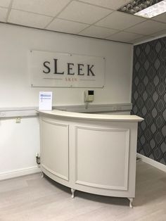 a white reception desk in an office with a sign on the wall that says sleek