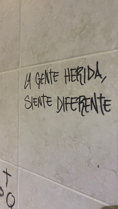 graffiti written on the side of a white tiled wall