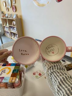 two pink bowls sitting on top of a table next to each other with writing on them